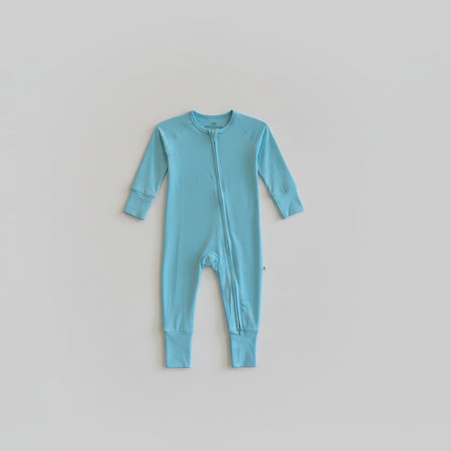Light blue onesie hanging on a hook against a brick wall.